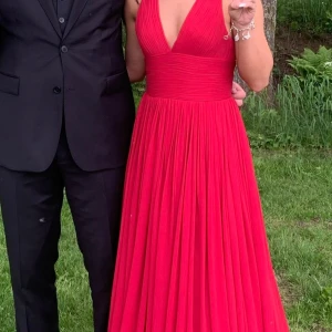 Röd balklänning  - Säljer min superfina balklänning ifrån Sofia Moore. Öppen i ryggen med fin tvistad detalj. Använd en kväll, tyvärr två små hål längre ner på klänningen som kan lagas men syns även inte så mycket när den är på💞 Insydd efter mina mått så ca 34-36 samt upplagd för mig som är 165cm med 9cm klack