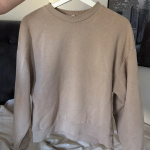 Beige sweatshirt - Säljer en stilren beige sweatshirt med rund hals och långa ärmar. Perfekt för en avslappnad look. Passar bra till jeans, joggers eller bara knuten över axlarna.