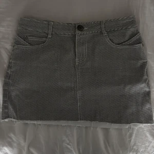 Jeanskjol - Snygg rutig kjol med klassiskt svartvitt mönster. Kjolen har en knapp och dragkedja framtill samt fina fickor både fram och bak. Perfekt för en stilren look! Ingen storlek men skulle tro att den passar s-m. Kanske även större då den är ganska stretchig.