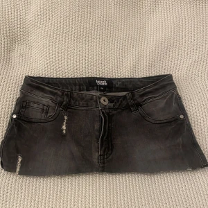 Svart jeanskjol från Heart - Lågmidjad snygg svart jeanskjol från Heart med slitna detaljer och klassisk femficksdesign. Kjolen har en knapp och dragkedja framtill för enkel påklädning. Kom med prisförslag vet inte orginal priset!! 