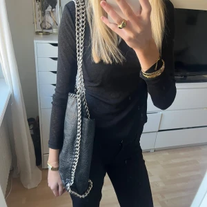 Svart axelväska från Tiamo - Snygg svart axelväska från Tiamo med silverkedja. Min gamla favorit väska så använd mycket men i väldigt fint skick och har inga synliga defekter,  rätt stor och får plats mer mycket! ❤️‍🔥 kommer tyvärr inte till användning längre.. 