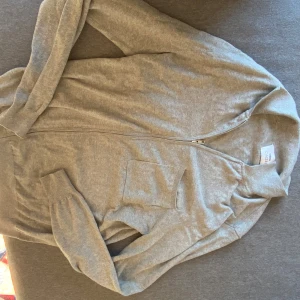 Grå kofta från Ciszere -          Säljer en stilren grå kofta från Ciszere i storlek S.            NYPRIS 1200 kr.           PASSAR NÅGON SOM ÄR mellan 175-185.    Koftan är tillverkad av 95% bomull och 5% kashmir, vilket gör den både mjuk och bekväm. Den har en dragkedja framtill och långa ärmar. Perfekt för en avslappnad look.