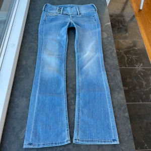 Diesel jeans  - Säljer ett par så himla snygga jeans från diesel med ett coolt knäppe. De är utsvängsa och lågmidjade. Innerbenslängd: ca 81 cm midjemått: ca 42 cm midjehöjd: 20 cm. Jeansen är strechiga.  W 29 L 30 Skriv för mer info💕