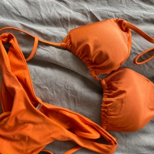 Orange bikini med knytband - Snygg orange bikini med knytband. Perfekt för soliga dagar på stranden eller vid poolen. Toppen har justerbara band för bästa passform.