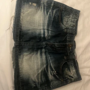 Jeanskjol från Sublevel - Snygg jeanskjol från Sublevel med slitna detaljer och klassisk femficksdesign. Kjolen har en cool tvättad look och är perfekt för en avslappnad stil. Den har en kort längd och rå kant nedtill.