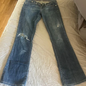 lågmidjade bootcut jeans levis  - Säljer ett par blå jeans med slitningar och bootcut-stil. De har en låg midja och klassisk femficksdesign. Perfekta för en avslappnad look. passar mig som är 165 och har strl xs-s pris går att diskutera 