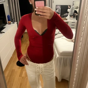 Röd långärmad v-ringad body  - Säljer en tight röd långärmad body med djup v-ringning. Sitter figurnära och har en clean, enkel design utan synliga detaljer. Perfekt att styla med jeans eller kjol för en snygg look. Helt ny och oanvänd!!😍