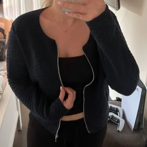 Mörkblå quiltad overshirt från Soda - Quiltad mörkblå overshirt från Soda med rund halsringning och silverfärgad dragkedja. 