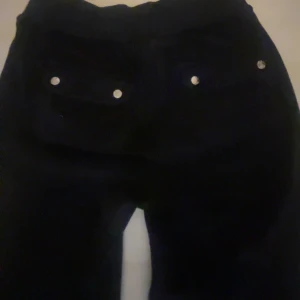 Juicy couture byxor - Svarta mjukisbyxor med broderad logga på benet. Mjukt material som är skönt att ha på sig. Fickor med tryckknappar bak.
