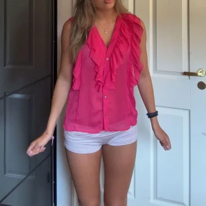 Rosa volangblus från Zara - Säljer en snygg rosa blus från Zara med volanger längs v-ringningen och axlarna. Den är oanvänd och perfekt till skolstarten💕