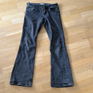Svarta low waist bootcut jeans  - Snygga svarta/gråa low waist bootcut jeans från Gina Tricot i storlek 158. Jeansen har klassisk femficksdesign, två knappar i midjan och dragkedja. Materialet är mjukt denim med en snygg grå svart look. Jeansen matchar med typ till allt och sitter väldigt skönt 