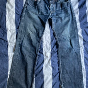 Diesel Larkee jeans blå W30 L32 - Säljer ett par klassiska blå Diesel Larkee jeans med raka ben och snygga slitningar. Jeansen har fem fickor, tydliga sömmar och coola detaljer på bakfickorna. Tillverkade i robust denim som ger en tidlös look.