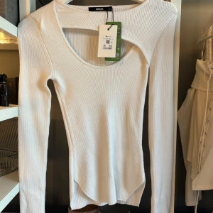 Vit ribbad långärmad topp BikBok - Supersnygg vit ribbad långärmad topp från BikBok med unik cut out-detalj vid halsen. Figurnära passform och stretchigt material som sitter perfekt. 