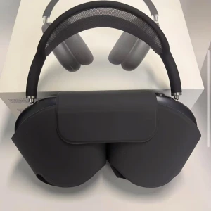 Airpod Max midnightblack - Bilderna visar ett par svarta over-ear hörlurar med modern design och mjuka öronkuddar. Produkten levereras med ett skyddsfodral och originalförpackning. Perfekt för dig som älskar musik och vill ha stilrena hörlurar med hög komfort.