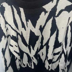 Svartvit stickad tröja från Monki - Cool stickad tröja från Monki i storlek S med svartvitt zebramönster. Tröjan har rund halsringning och är perfekt för dig som vill sticka ut med en edgy vibe. Mjuk och skön att bära, passar till både jeans och kjol.