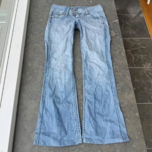 Ljusblå vintage lågmidjade bootcut jeans  - Snygga ljusblå jeans från R.MARKS. Några skavanker som visas på de sista bilderna, ena knappen är av men det märks inte mycket. Midjemått 38, grenlängd 18 och innerbenslängd 77,5💗