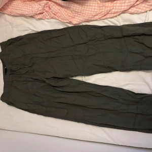 Olivgröna byxor från 157, storlek M - Säljer ett par olivgröna byxor från 157 i storlek M. Byxorna har resår i midjan och är tillverkade i ett lätt och skönt bomullstyg. Perfekta för en avslappnad och chill stil. Passformen är loose och modellen är rak i benen.