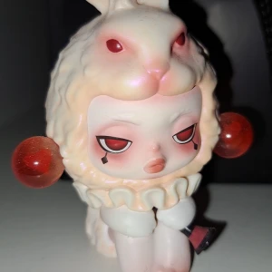 Pop Mart SKULLPANDA  - Bilderna visar en konstnärlig samlarfigur från POP MART. Figuren har ett unikt och uttrycksfullt utseende med kaninhuvud och röda detaljer. Ingen box kommer med, endast figuren. 