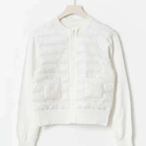 Vit quiltad dunväst med dragkedja - Snygg vit dunväst med quiltad framsida och två fickor. Västen har dragkedja framtill och ribbade muddar vid hals och nederkant. Perfekt för lager-på-lager och ger en clean look.