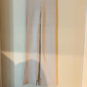 Beige stickade byxor med slits - Beige stickade byxor med rak passform och slits nertill på benen. 