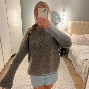 Grå stickad tröja från & Other Stories - Supermysig grå stickad tröja från & Other Stories, med fluffig känsla och rund hals. Perfekt för lager på lager och chill höst- och vinteroutfits. Långärmad och loose fit för en avslappnad vibe.