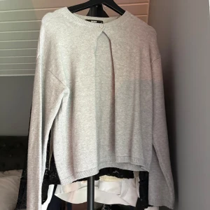 Ljusgrå stickad tröja från BikBok - Supermjuk ljusgrå stickad tröja från BikBok med rund halsringning och en snygg knappdetalj framtill. Långärmad och i en relaxed passform, perfekt att slänga på sig när det är kyligt ute.💘