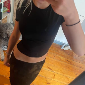 Svart croppad t-shirt topp - Storlek xxs men passar som xs Enkel och stilren svart croppad t-shirt med korta ärmar och rund hals. Sitter tight och har en klassisk passform som funkar till allt. Perfekt för dig som gillar minimalistisk stil och vill ha en basic topp i garderoben.