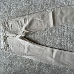 Beige jeansbyxor från Dobber W29 L32 - Snygga beige jeansbyxor från Dobber i klassisk femficksmodell. Byxorna har raka ben och normal passform, tillverkade i bomullsmaterial. Perfekta för dig som gillar stilrena och ljusa jeans med enkel look.