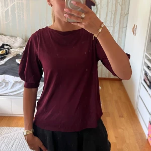 Vinröd topp med puffärm - Vinröd topp med rund halsringning och snygga puffärmar som ger en trendig siluett. Modellen är rak och lite loose, perfekt till både jeans och kjol. Tunn och mjuk i materialet, superenkel att styla för en cool look. Går att ha armarna på olika sett försökt få med de på bild två och tre❤️ 