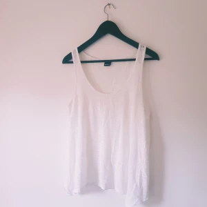 Vit linnetopp från Gina Tricot L - Säljer en vit linnetopp från Gina Tricot i storlek L. Toppen är ärmlös med rund halsringning och har en snygg omlott-detalj baktill som ger en cool och luftig känsla. Perfekt för varma dagar och enkel att styla till jeans eller shorts.  Helt skick dock noppror
