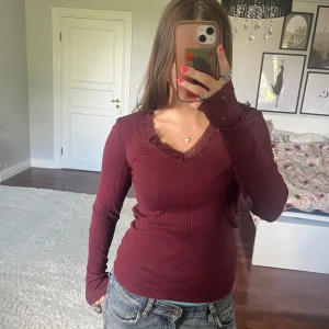 Vinröd ribbad topp❤️ - Supersnygg vinröd långärmad topp från Vero Moda med ribbad struktur och v-ringning med spetsdetalj. Sitter tajt och är perfekt att styla med jeans eller kjol. Materialet är mjukt och stretchigt, vilket gör den riktigt bekväm.💕 Tröjan har tecken på användning