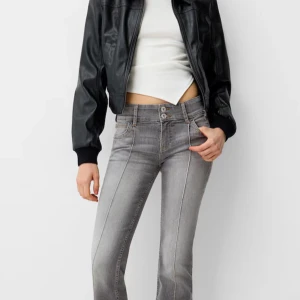 Grå bootcut jeans med pressveck - Snygga grå jeans med bootcut och markerade pressveck framtill. Låg midja och klassisk femficksmodell med dubbla knappar i linningen. Jeansen har en cool tvättad look och kontrastsömmar. Perfekta för dig som gillar en trendig och avslappnad stil.