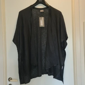 Kofta från Vero Moda - Helt ny mörkblå/grå kofta/poncho i oversized modell. Nypris 180 kr.  Den är öppen framtill och har korta, vida ärmar. Stickat, mjukt material. Färgen syns bäst på andra bilden. 