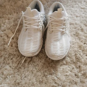 Vita sneakers med mesh och snörning - Säljer ett par fräscha vita sneakers med cool mesh-design och snörning. Skorna har en sportig vibe med rund tå och platt sula, perfekt för dig som gillar stilrena och bekväma skor. Lätta och luftiga, passar perfekt till streetwear eller casual outfits. Storlek 40. 