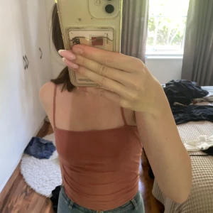 Rostrosa linnetopp med smala axelband - Supersnygg rostrosa linnetopp från H&M med smala axelband och rak halsringning. Toppen är figurnära och enkel i modellen, perfekt att styla med jeans eller kjol. Mjuk och skön bomullskänsla som passar perfekt till varmare dagar.