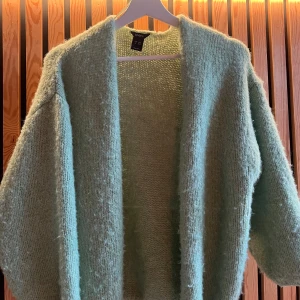 Ljusgrön stickad kofta från Lindex - Mysig ljusgrön stickad kofta från Lindex i oversized modell. Koftan har en öppen front utan knappar och är tillverkad i ett fluffigt, mjukt material. Perfekt att slänga på sig över en t-shirt eller topp för extra värme.Tveka inte på att höra av er vid frågor 