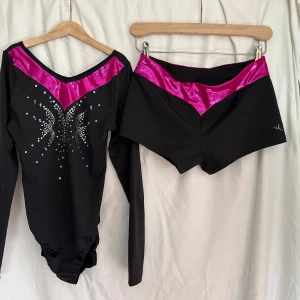 Svart och rosa gymnastikset  - Säljer en svart långärmad gymnastikdräkt med tryckta paljetter framtill och metallicrosa detalj vid halsen. Storleksangivelse saknas, men jag chansar på att den passar strl 38/40