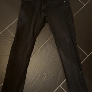 Svarta Replay Anbass jeans herr - Svarta Replay Anbass jeans med klassisk femficksdesign och smal passform. Jeansen är tillverkade i stretchig bomullsdenim för extra komfort och har diskreta sömmar och metallknapp framtill. Perfekta för dig som gillar en clean och stilren look. Använda ungefär 10 gånger. MVH/Felix