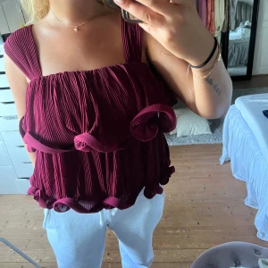 Lojsan Wallin topp - Supersöt vinröd/rosaröd blus med breda axelband och plisserat tyg. Toppen har volangdetaljer längs både över- och nederkant som ger en unik och lekfull look. Köpt på nakd och är nu slutsåld. Endast använd en gång❤️