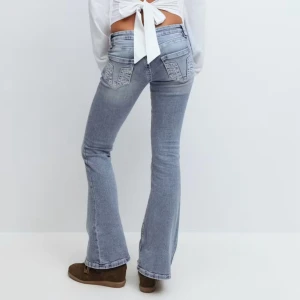 Ljusblå bootcut jeans med broderade fickor - Super low snygga jeans som är jätte populära. Säljer då dom va lite för små men helt slutsålda i stolek xs i tall. Helt nya med prislappen kvar