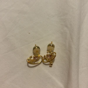 Guldiga örhängen med planetmotiv - Supersöta guldiga örhängen i form av små planeter med gnistrande stenar och en liten hängande stjärna. De har en unik design med glittriga detaljer och passar perfekt för dig som gillar rymdtema och vill sticka ut lite extra. Aldrig använda då jag egentligen inte passar i guld men tyckte de var så fina :,) 