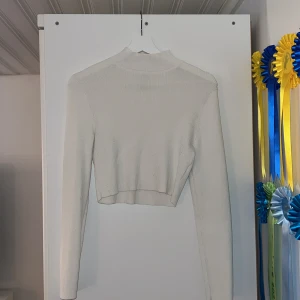 Vit croppad ribbad tröja H&M Divided - Säljer en vit croppad tröja från H&M, Divided i stl L. Tröjan är ribbstickad med lång ärm och hög hals, perfekt för en clean och trendig look. Sitter tajt och är superenkel att styla med jeans eller kjol. Endast använd vid några tillfällen, lite nopprig.