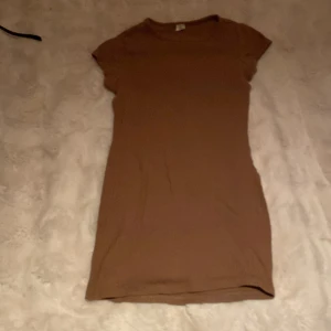 Brun ribbad lång T-shirt från SHEIN - En enkel och snygg brun ribbad lång T-shirt  från SHEIN. T-shirten har korta ärmar, rund halsringning och är figurnära i modellen. Perfekt för dig som gillar en basic och stilren look. Materialet är mjukt och stretchigt för extra komfort.