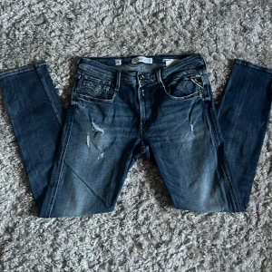 Replay Anbass jeans med slitningar - Säljer dessa sjukt snygga Replay jeansen i modellen Anbass med slitningar. Jeansen är i fint skick, inga defekter. De är i storlek 32/30 och är slim fit. Bara att skriva över frågor och funderingar.