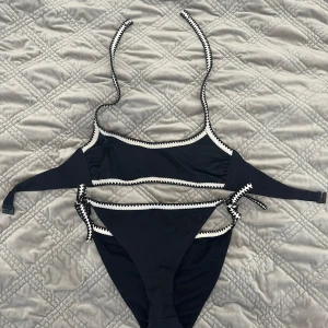 Svart bikini från Calzedonia - Vi kan komma överens om priset 😀😀😀Snygg svart bikini från Calzedonia med vita, sicksack-mönstrade kanter. Bikinin har smala axelband och knyt i sidan på underdelen. Perfekt för stranden eller poolen, stilren och enkel design som ändå sticker ut.