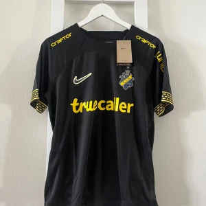AIK svart matchtröja Nike M - AIK:s officiella matchtröja från Nike i svart med gula detaljer och tryck. Kortärmad modell i lätt och ventilerande Dri-FIT-material. Klubbmärke på bröstet, sponsorloggor och unika detaljer på ärmsluten. Perfekt för dig som vill visa ditt AIK-stöd.