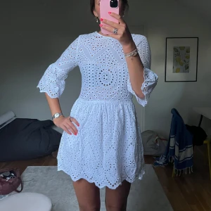 Vit broderad kortklänning med volangärm - Superfin vit kortklänning med broderade detaljer och hålmönster. 