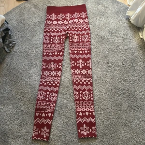 Röda leggings med julmönster - Mysiga röda leggings med vitt julmönster, snöflingor och hjärtan. Perfekta för vintern och julen, med hög midja och stretchigt material som sitter tight och bekvämt. Perfekt för att chilla hemma eller mysa runt i december.