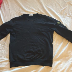 Stone Island strl 156 - En svart stone Island crewneck i storlek 156/12 men går upp till 165. Den är i mycket bra skick förutom att sömmen har lossnat lite vid slutet av ärmen men det är något som lätt går att fixa. Pris 430kr men går att förhandla.👍🏼