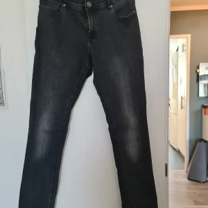 Svarta jeans från Jack & Jones 176 - Säljer ett par svarta jeans från Jack & Jones i storlek 176. Jeansen har en klassisk femficksmodell, snyggt tvättad finish och raka ben. Perfekta för dig som gillar en stilren och enkel look.